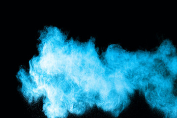 Abstract blue powder splatted on white background. Freeze motion of blue powder exploding on...