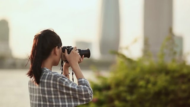 Vietnamese girl photographer takes pictures of nature in the city center at sunset