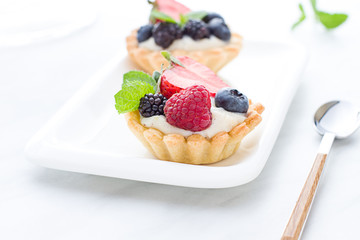 Mini tarts on the plate close up. Homemade dessert with delicious catalonian traditional cream and fresh berries