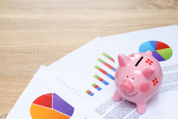 Pink piggy bank with graph on wooden desk - growing interest rate concept.