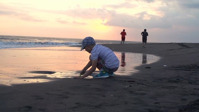 Young boy playing with sand by sea, super slow motion 120fps 
