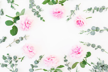 Floral round frame of pink roses and eucalyptus branches on white background. Flat lay, top view