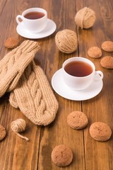 Coffee, mittens and oat cookie on wood