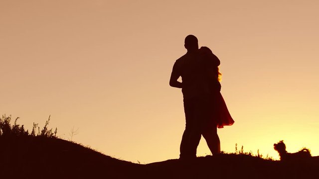 Couple in love nature dancing silhouette at sunset and kissing. Loving man and woman with dog dancing silhouette slow motion video