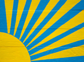 Sunburst in yellow and blue on wood panel background