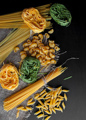 Mixed raw pasta on black background