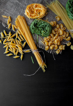 Mixed raw pasta on black background