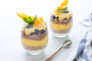 Homemade granola with mango and greek yogurt in modern glasses. Close up