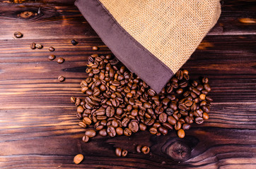 Roasted coffee beans in sack on wooden table. Top view