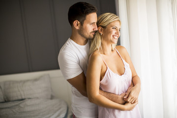 Lovely young couple standing by the window at morning