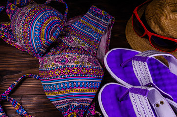 Swim suit, hat, sunglasses and flip flops on a wooden table. Summer vacation concept