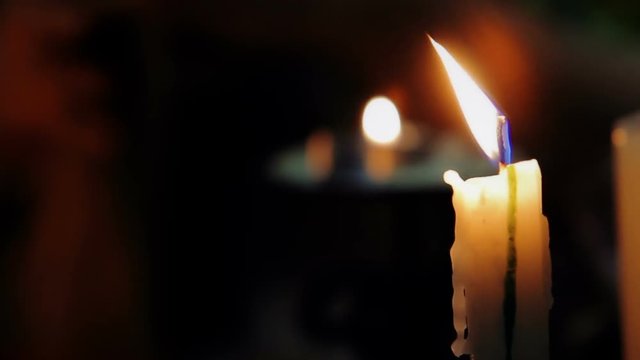 Charlatan witch holding in hands book of black magic, view on burning candle