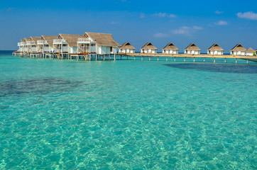 Clear crystal water with luxury water villas in blue sky, Maldives. Honeymoon destination in Asia.