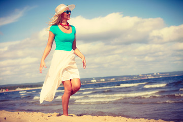 Blonde woman wearing dress walking on beach