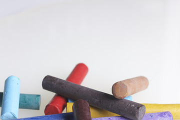 Crayons pastels in different colors. Lying in a box in their places. On a white background. In a chaotic order.