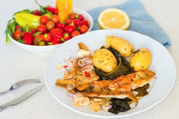 Fried fish with boiled potato and seaweed wakame.