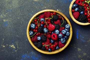 Colorful summer berries in assortment, black stone background, top view