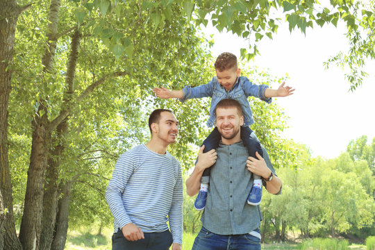 Smiling gay couple with son in park