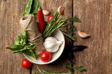 Composition with fresh herbs and vegetables on wooden background