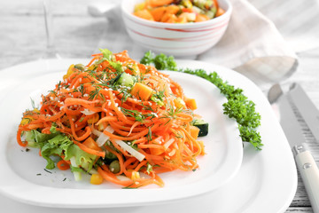 Plate with delicious spicy carrot spaghetti on table