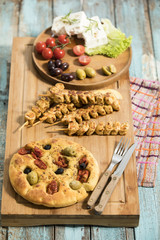 gegrillte Fleischspiesse, mediterranes Ofenbrot mit Oliven und getrockneten Tomaten, Schafskäse mit Rosmarin und Salatblättern garniert, Studio