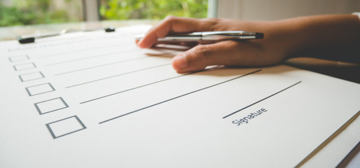 Close- up hand with pen on maintenance check paper and the format for filling in information in...