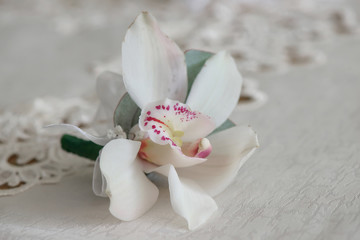 White orchid boutonniere small bouquet for buttonhole used for groom and wedding guests positioned...
