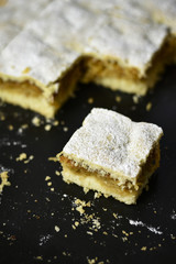 A cut piece of apple pie on black plate