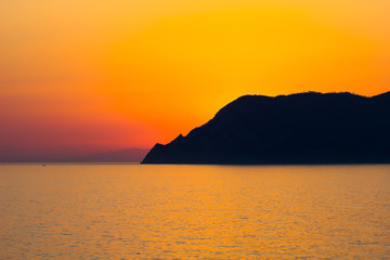 Obraz premium Natural Sunset, Sunrise over sea, mountain Bright Dramatic Sky And Dark Ground. Countryside Landscape Under Scenic Colorful Sky At Sunset Dawn Sunrise. Sun Over Skyline, Horizon. Warm Colours.