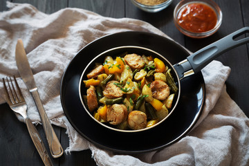 Fried potatoes with sausages, pepper and ketchup