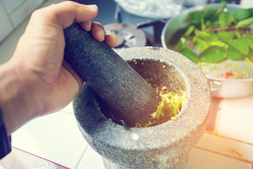 Close-up hand's person grinding chili by Stone mortar and pestle in the kitchen. Thai food concept.
