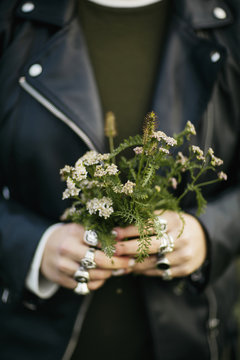 Detail of feminine hands with lots of rings holding wildflowers bouquet