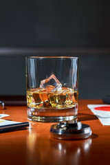 glass of Scotch with ice on the desktop among contracts and documents