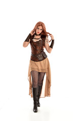 Fototapeta premium full length portrait of a red haired lady wearing steampunk inspired outfit, standing pose against a white background.