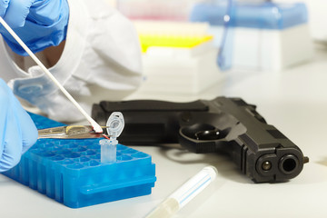 Criminologist lab technician working on forensic DNA analysis from handgun
