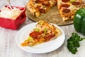 Pepperoni Pizza Slice With Green Pepper and Parsley and Parmesan Cheese