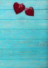 Valentine's Day. Decorative wicker hearts of burgundy color on azure wood background.