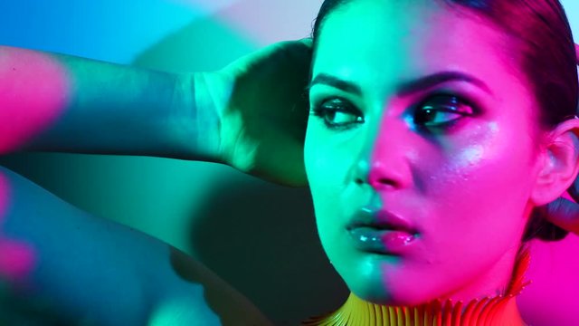 Fashion model woman in colorful bright lights posing in studio, portrait of beautiful sexy girl with trendy make-up and manicure. 4K UHD video 3840x2160