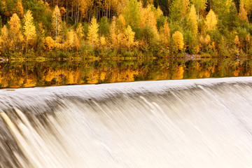 Landscape with autumn forest, dam on the river and reflection, Finland