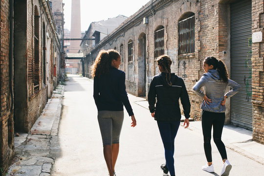 Back view of group of athletes walking on the street after workout.
