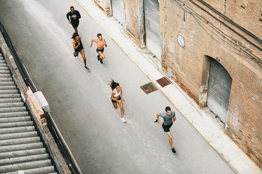 Group Of Athletes Running On The Street From Above.