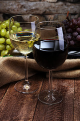 Red Wine bottle and white wine with grapes and glasses on wooden