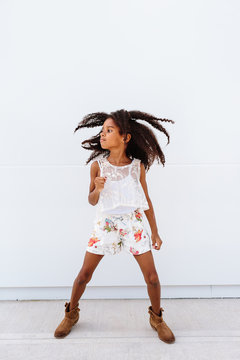 A cute African American girl jumping up against a white background