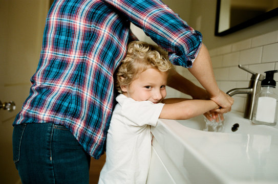 mother helps child wash hands
