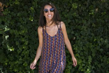 portrait of a young beautiful woman wearing summer outfit. Green background. Sunglasses. Sunny. Lifestyle