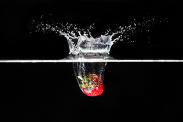 A strawberry splashing into water