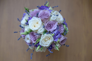 Lavender and roses with purple hues floral arrangement set on a table, view from above