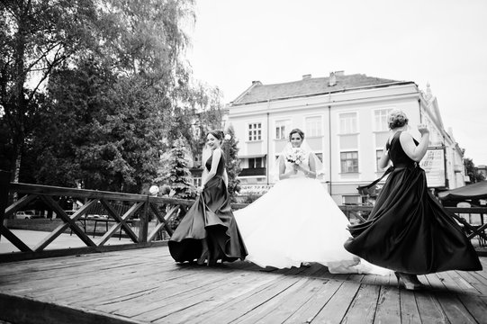 Fabulous bride walking, posing and having fun with her bridesmaids in the downtown on a wedding day. Black and white photo.
