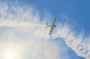 White turboprop airplane with a trace of white smoke against a blue sky