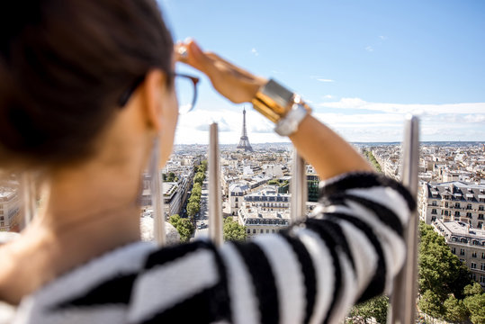 Young woman tourist enjoying great cityscape view on Paris during the sunny weather in France. Image focused on the background woman is out of focus